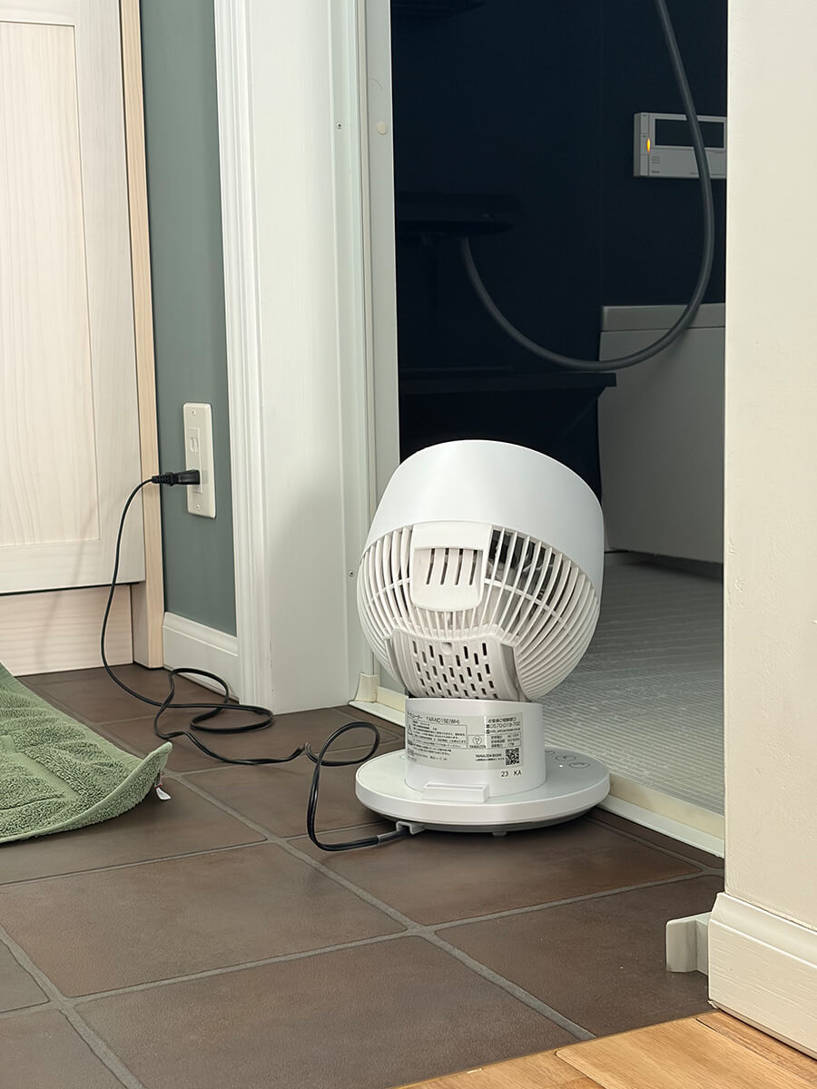 脱衣所から浴室にサーキュレーターで風を送って換気する様子